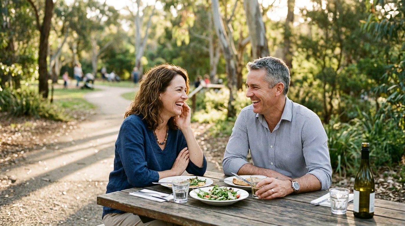 Couple in their forties laughing over lunch on a path through the Adelaide Parklands in Adelaide in the afternoon